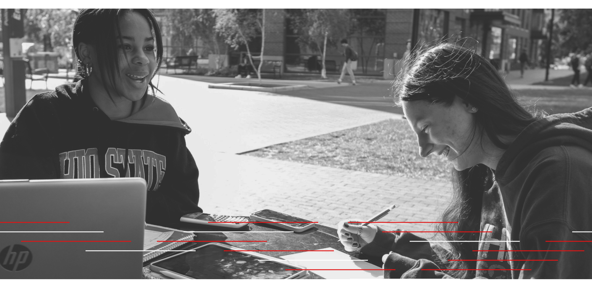 Two students sitting outside laughing and working