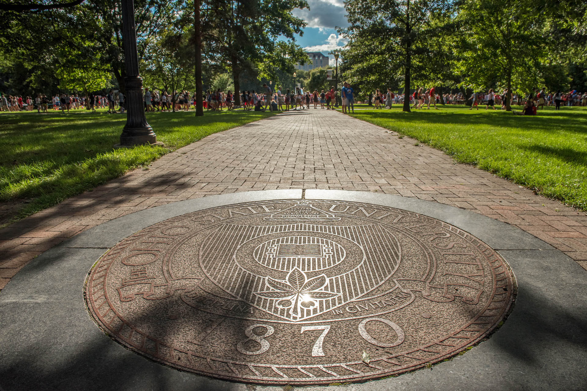 Picture of the seal of The Ohio State University on a sign with a brick building in the background.